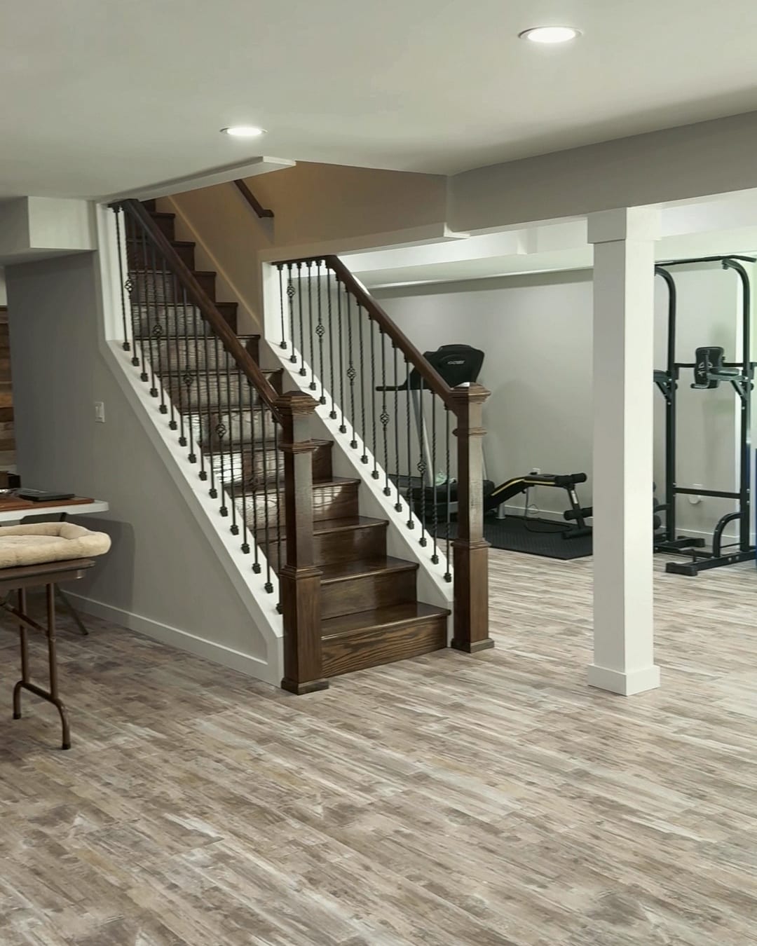 A finished basement: new oak stairs with iron balusters, white posts and plank floors, a HomePro job