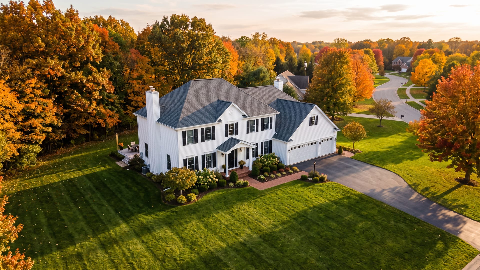 A finished two-storey colonial with a new charcoal shingle roof, seen from above at golden hour
