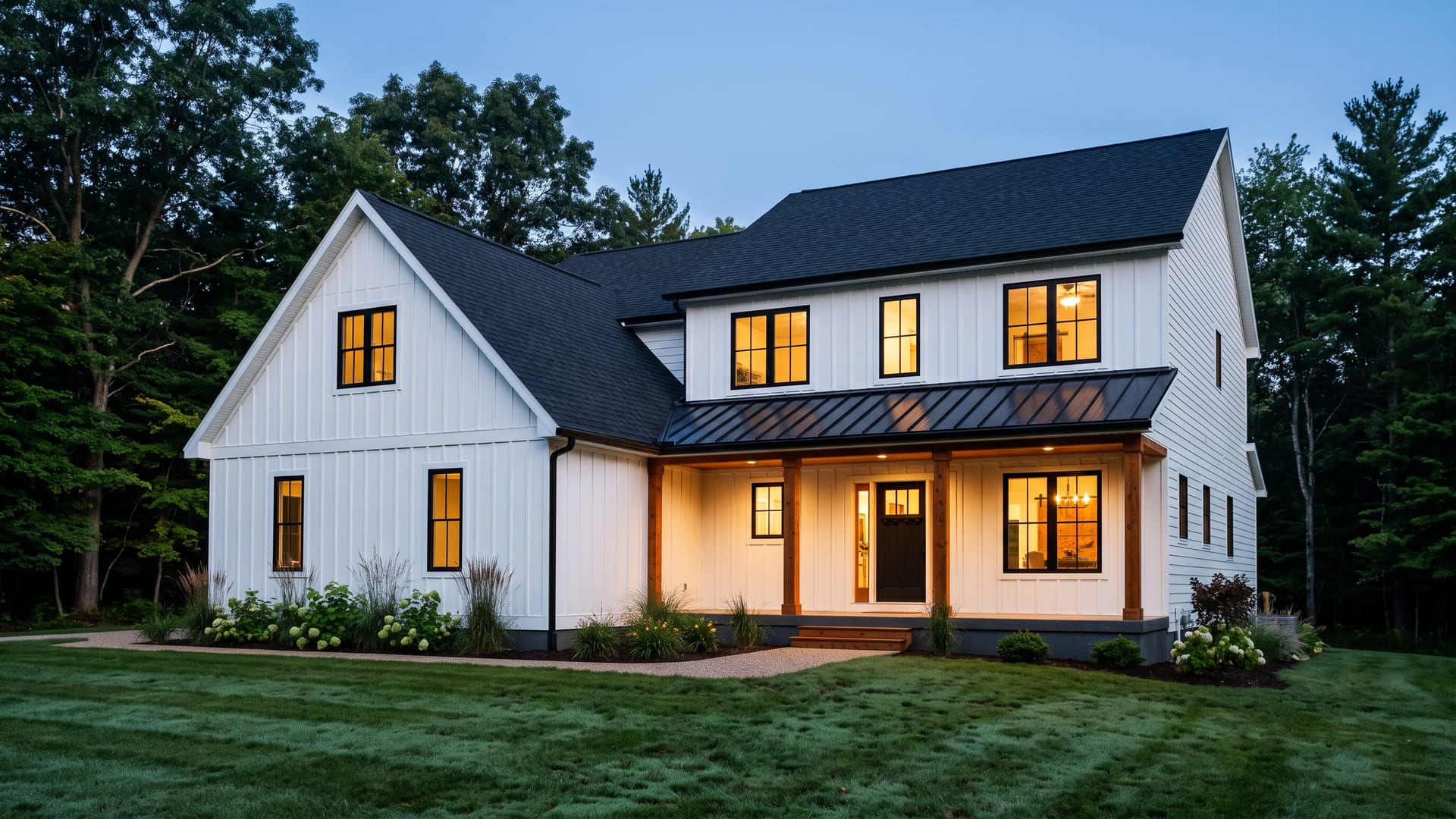 A modern farmhouse with new white board-and-batten siding and black windows at blue hour
